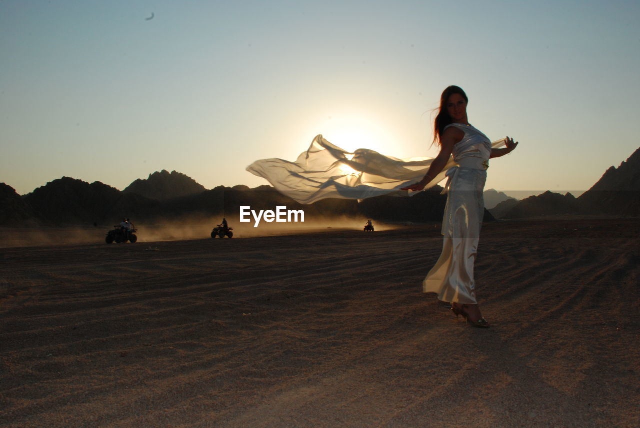 Full length of fashionable woman posing in desert during sunset