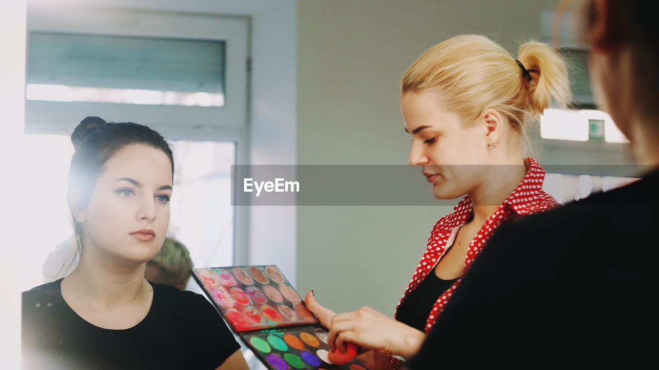 Beautician doing make-up of woman