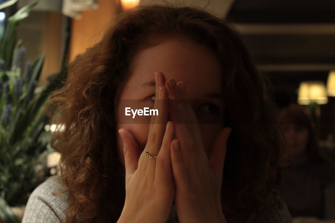 PORTRAIT OF WOMAN COVERING FACE WITH HAND IN HAIR