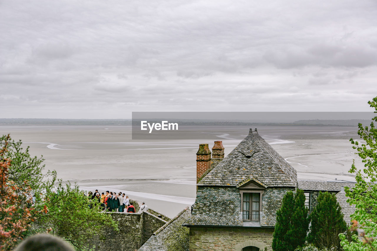 People on building by sea against sky