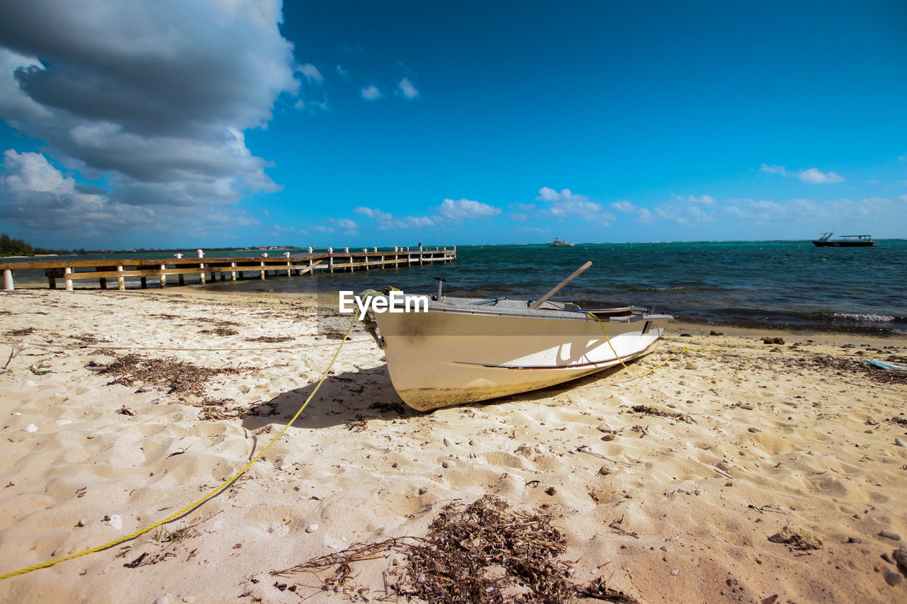 Boat moored on beach against sky