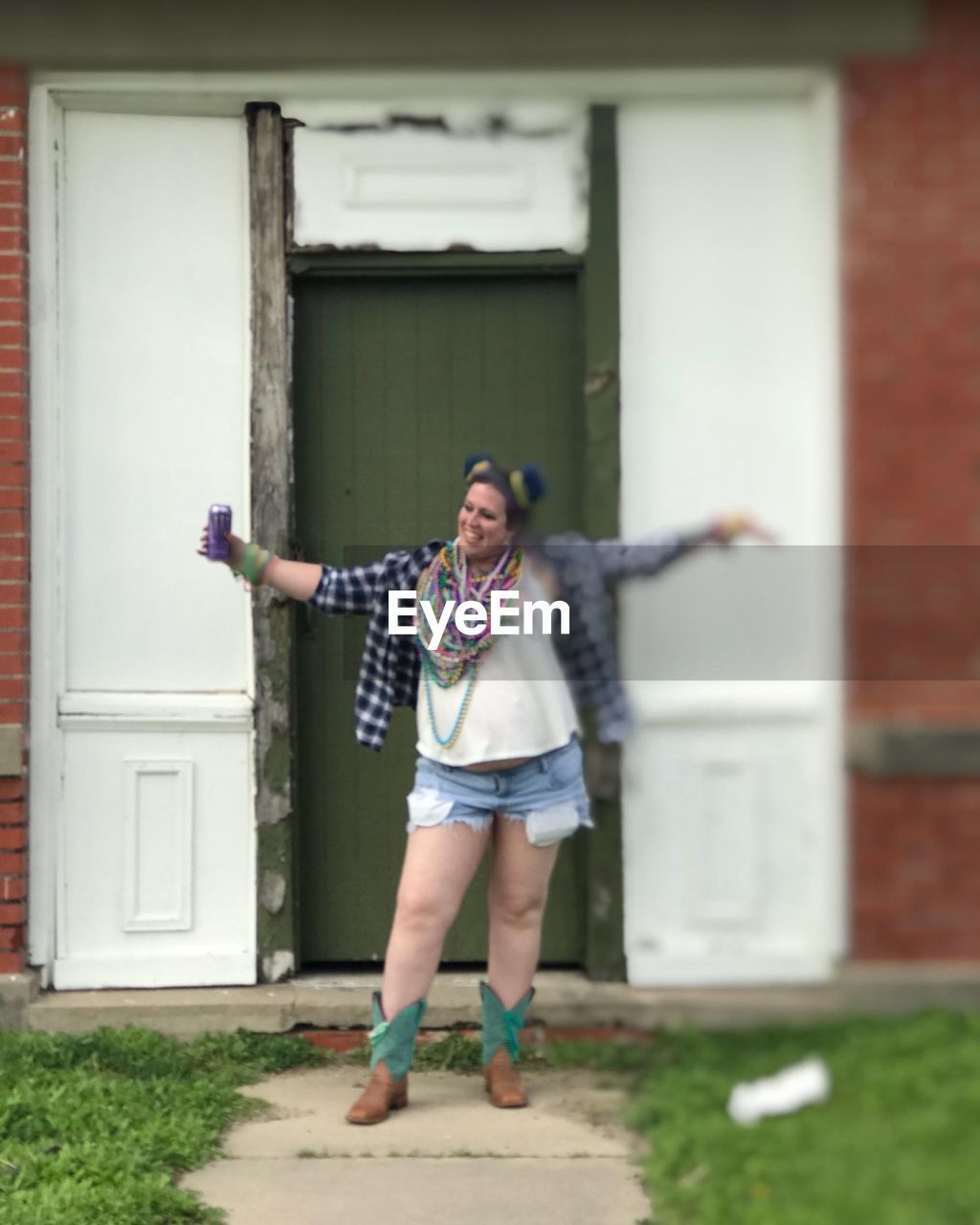 FULL LENGTH OF SMILING WOMAN STANDING BY BUILDING