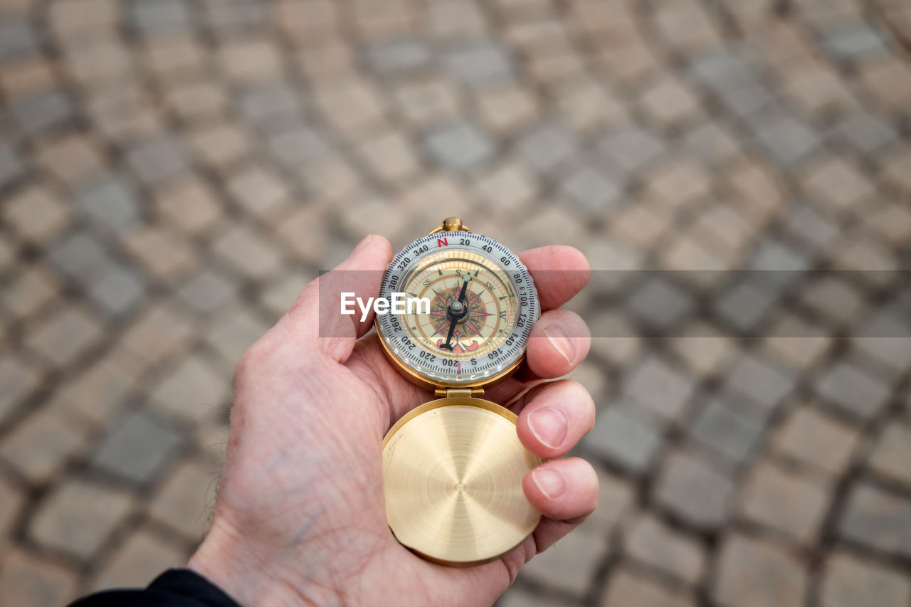 Close-up of hand holding navigational compass on footpath