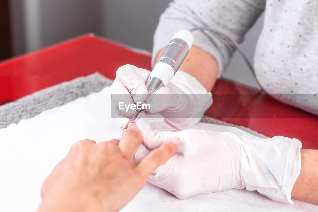 Midsection of beautician doing manicure of female customer in salon