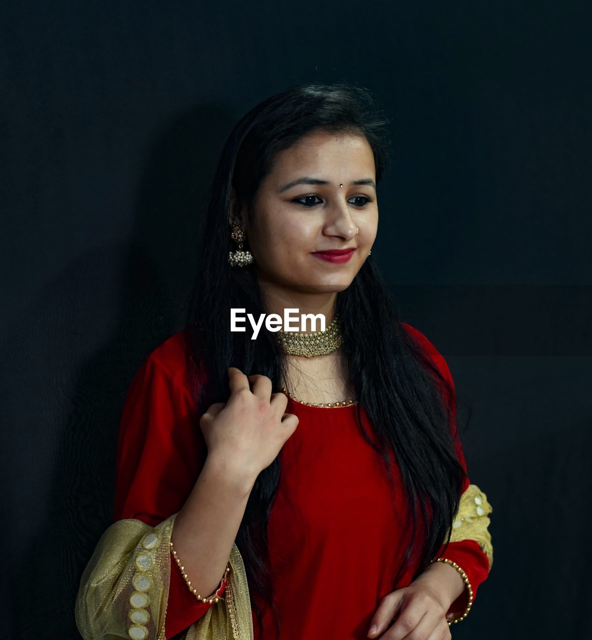 PORTRAIT OF A BEAUTIFUL YOUNG WOMAN AGAINST GRAY BACKGROUND