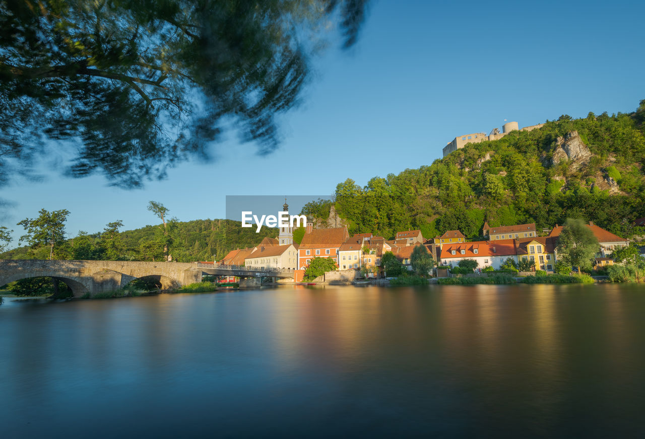 BUILDINGS BY RIVER AGAINST SKY