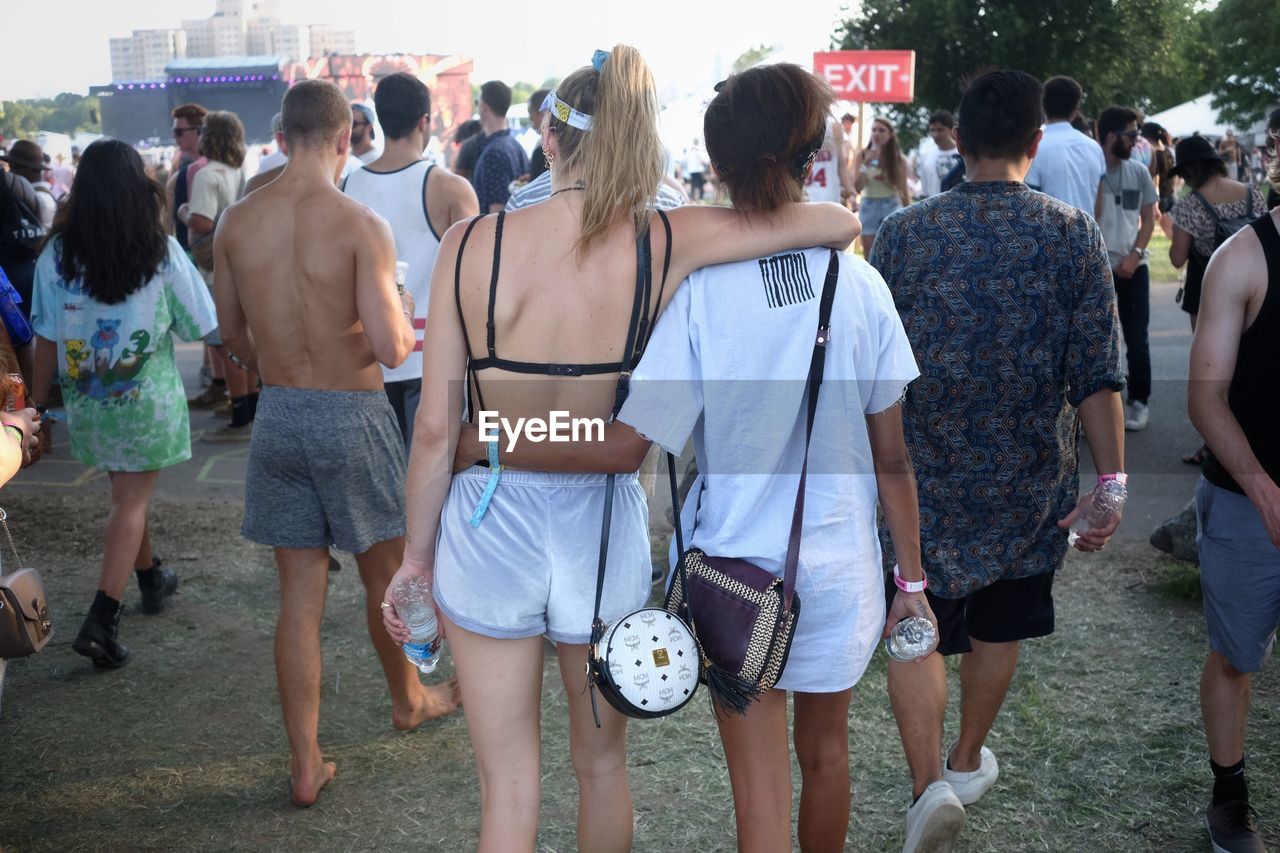 Rear view of two girls walking together at music festival