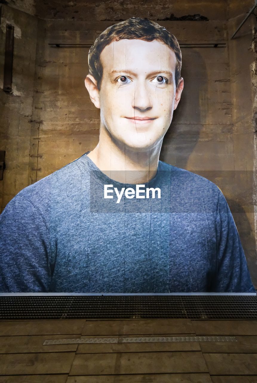 PORTRAIT OF YOUNG MAN WEARING EYEGLASSES STANDING AGAINST WALL