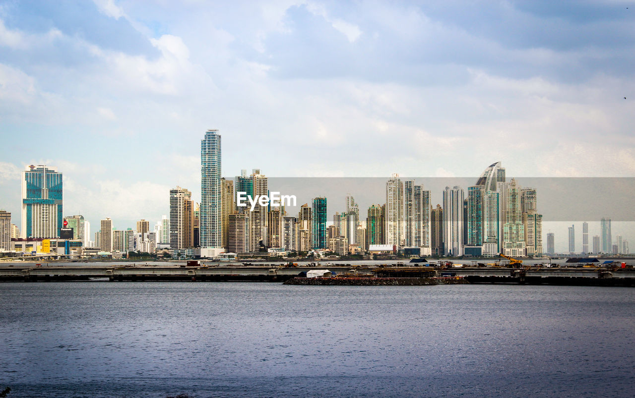 Sea by buildings against sky in city