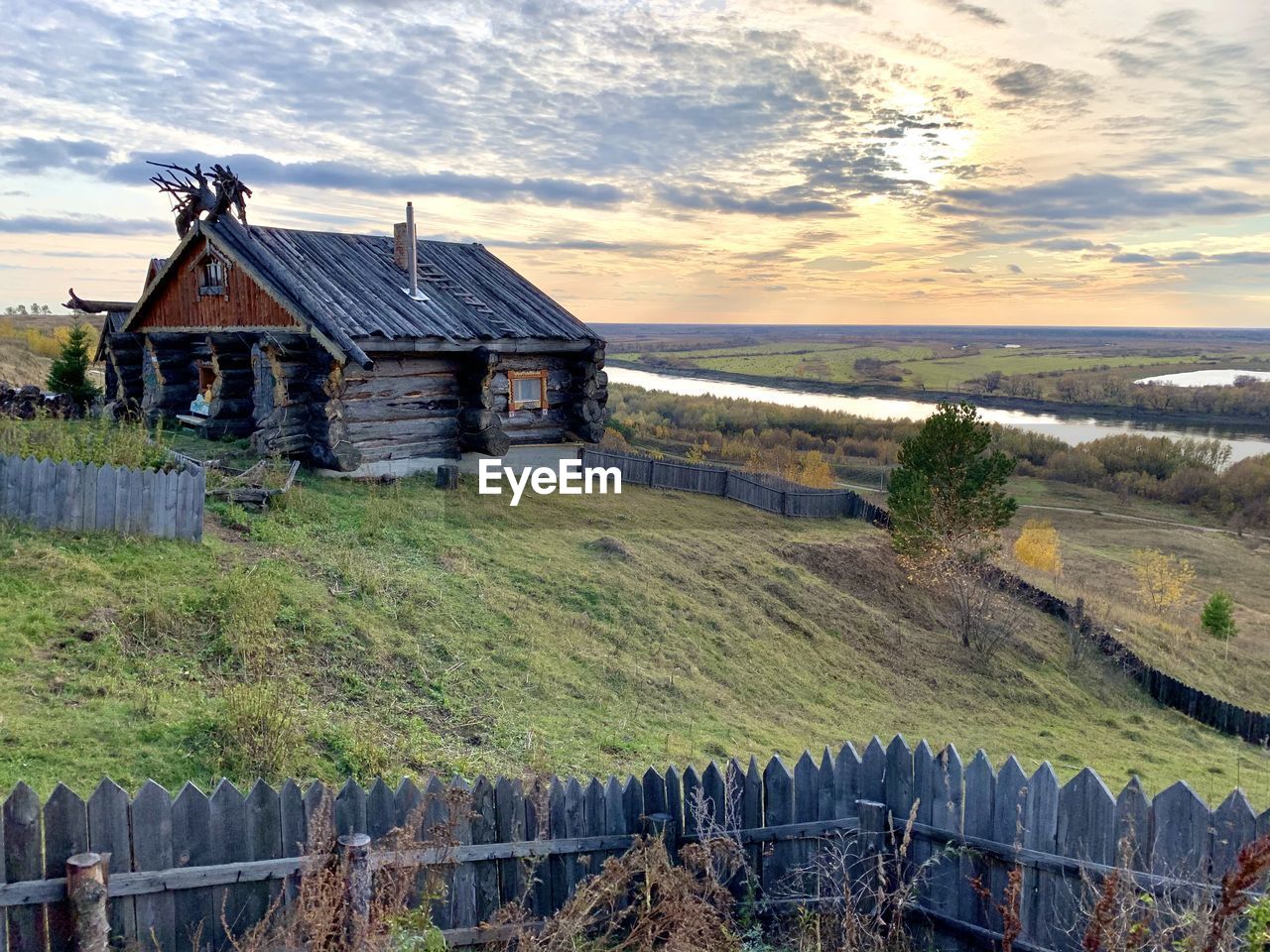 Houses by agricultural field against sky during sunset