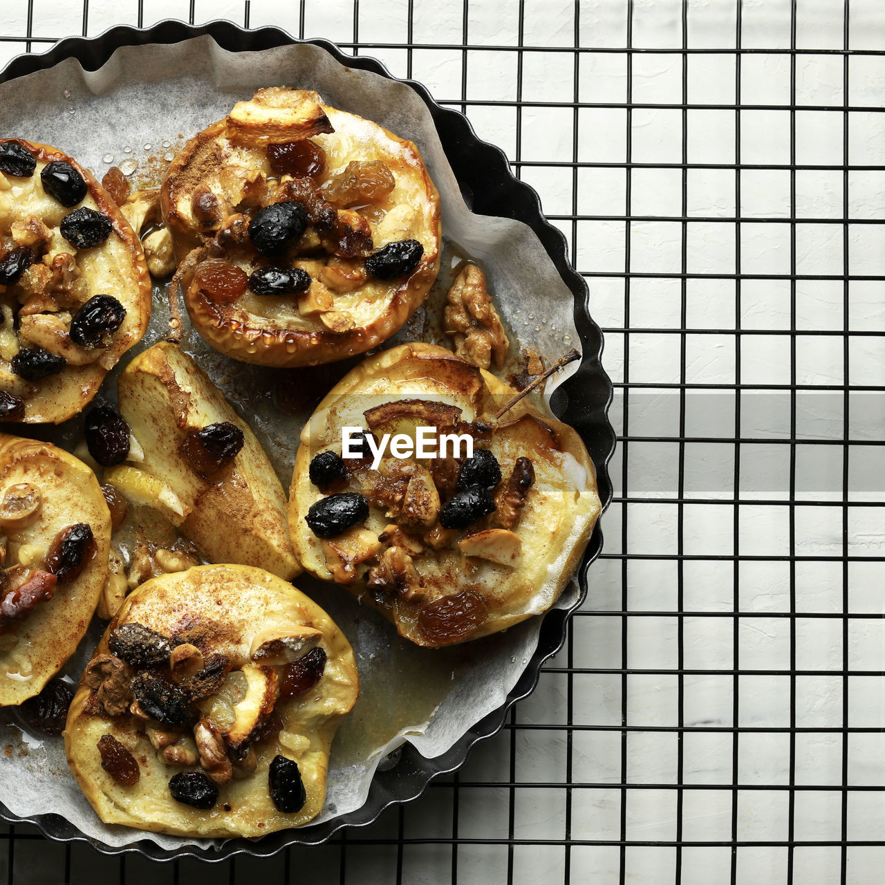 Baked apples stuffed with dried fruit, nuts, sultanas, cinnamon in a baking dish.