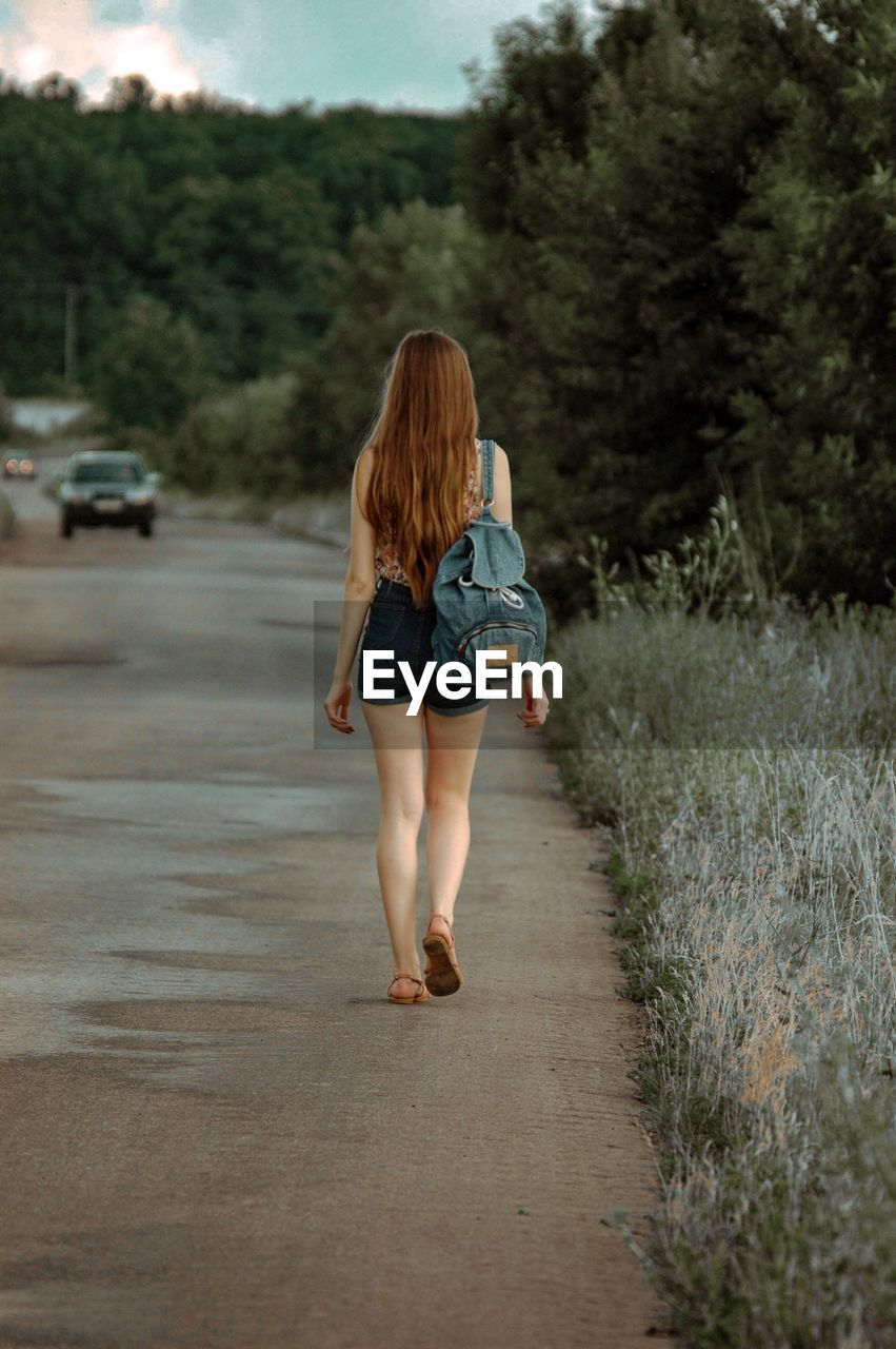 Rear view of woman walking on road