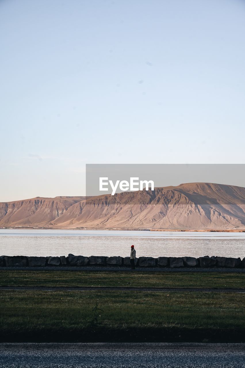 Full length of person standing by lake against mountain