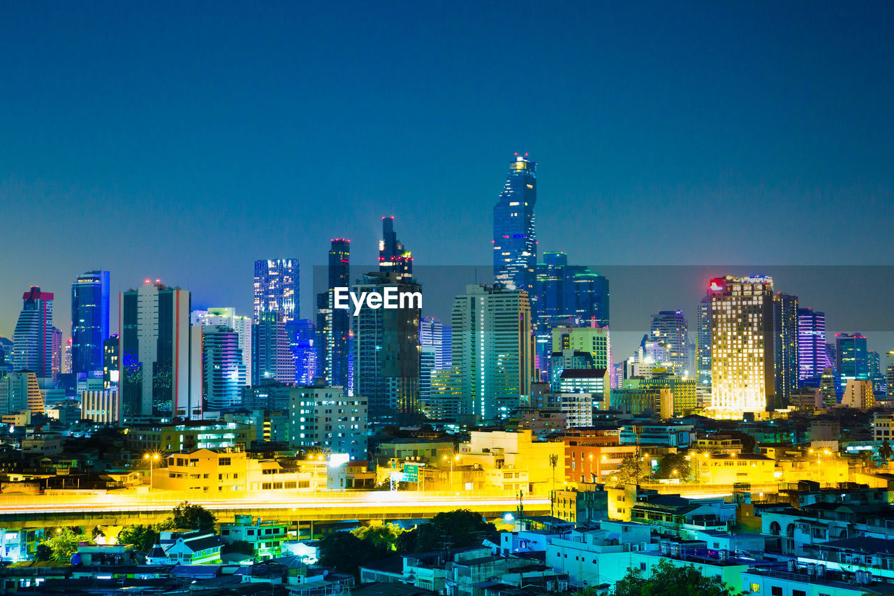 ILLUMINATED MODERN BUILDINGS AGAINST BLUE SKY