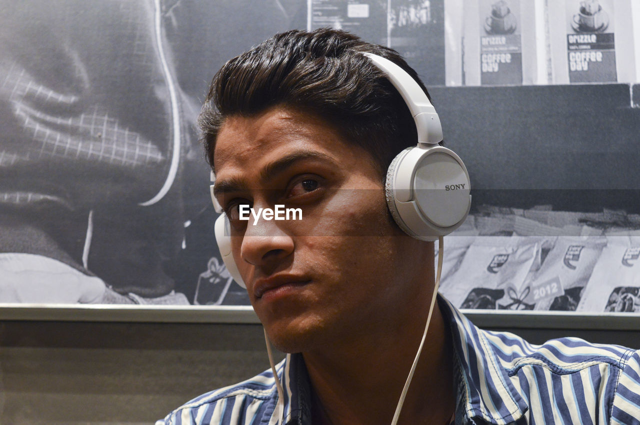 PORTRAIT OF YOUNG MAN LOOKING THROUGH CAMERA