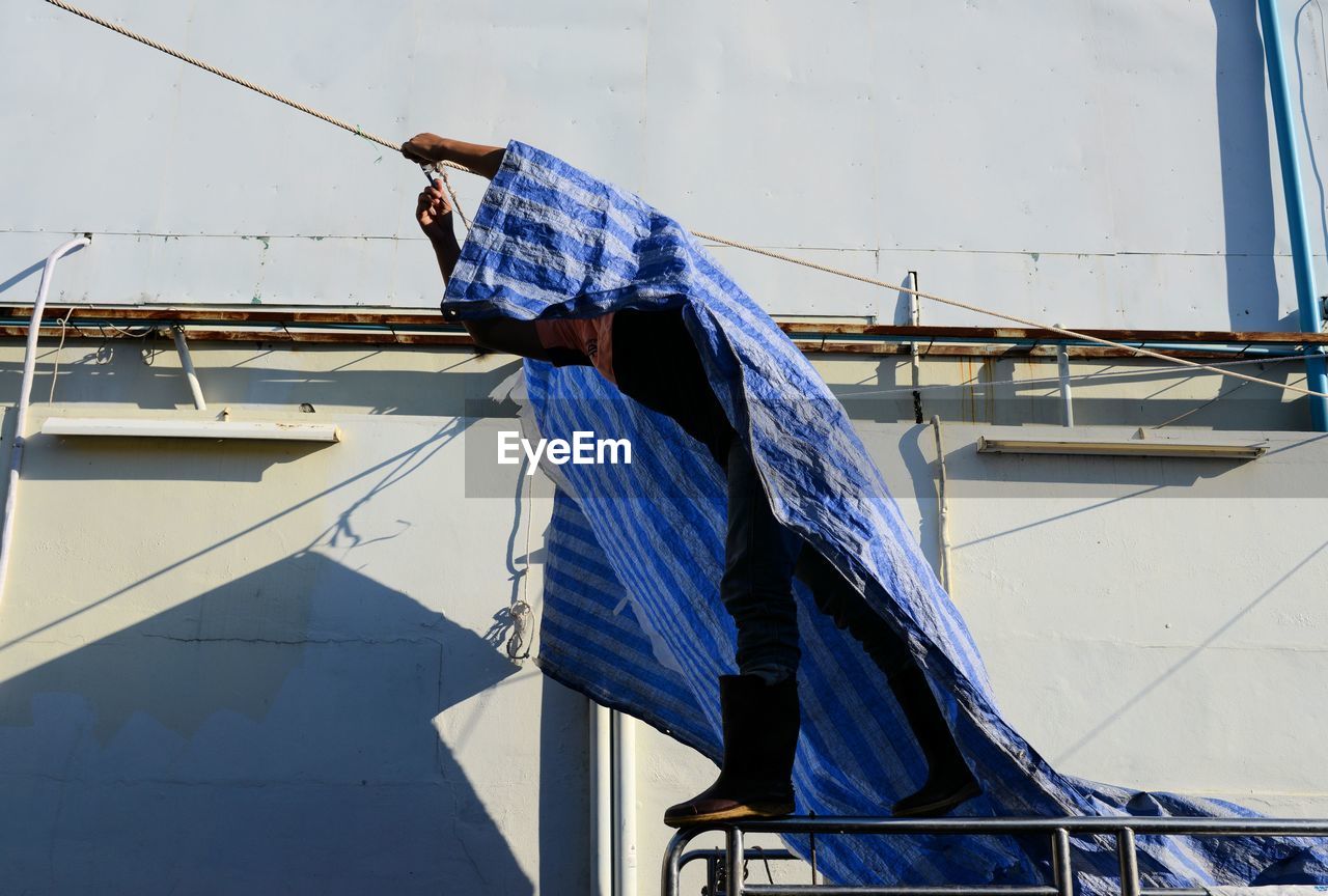 Man applying tarpaulin on rope