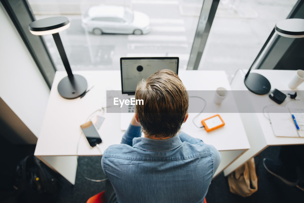 High angle rear view of businessman working at desk in office