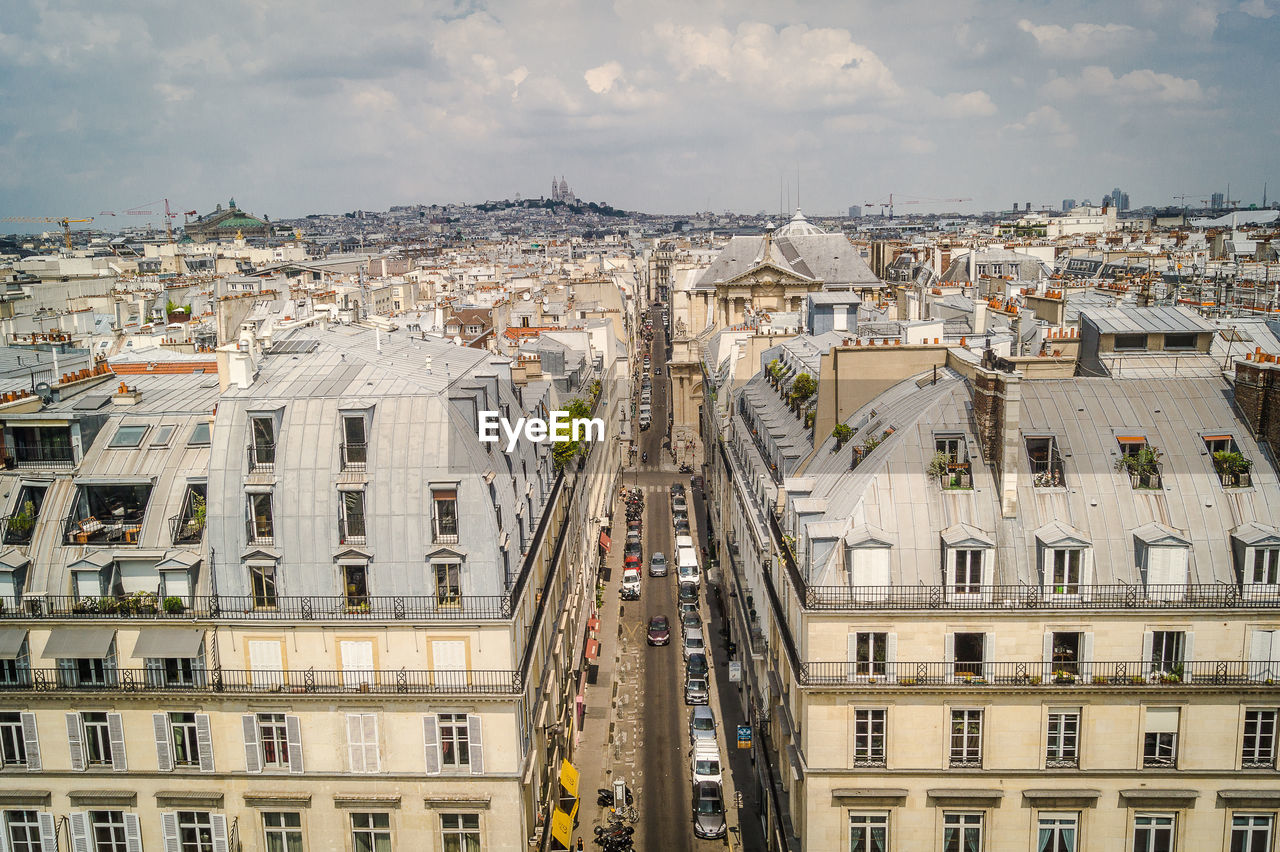 Aerial view of cityscape against cloudy sky during sunny day