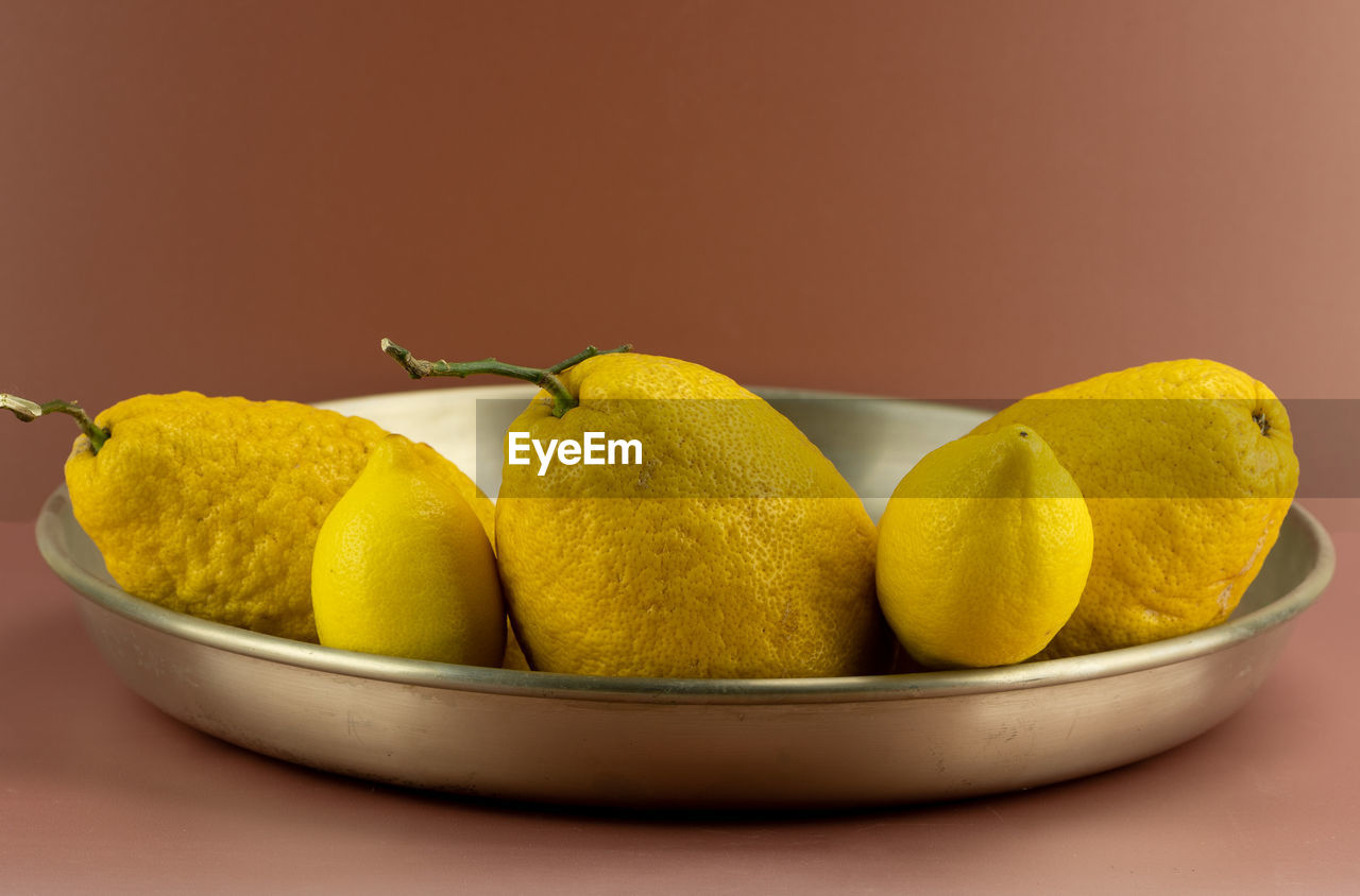 food, food and drink, healthy eating, fruit, wellbeing, pear, yellow, freshness, citrus, plant, produce, studio shot, indoors, citrus fruit, no people, bowl, group of objects, lemon, still life, colored background