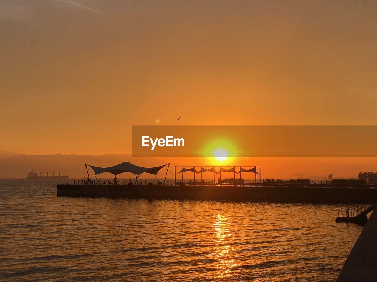 SILHOUETTE BOAT IN SEA AGAINST ORANGE SKY