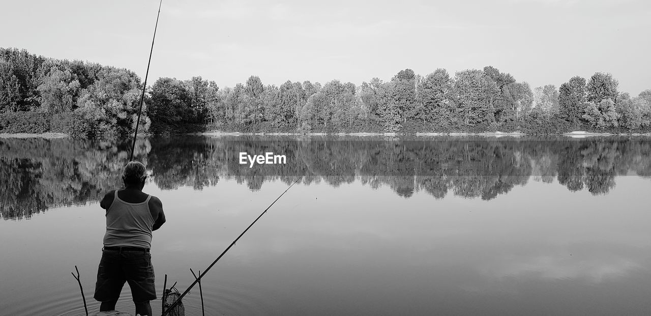 REAR VIEW OF MAN AGAINST LAKE