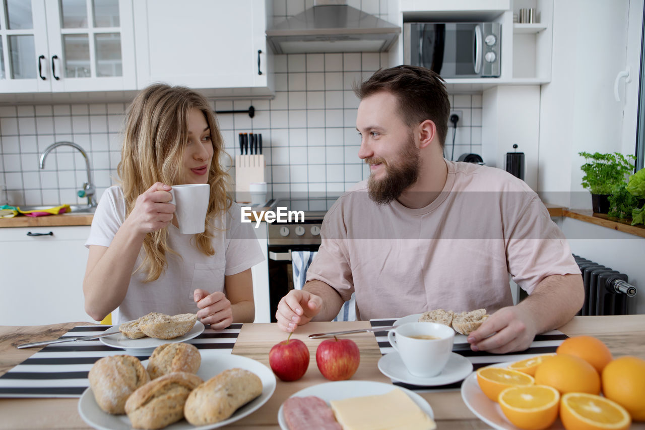 Smiling man and woman having breakfast home