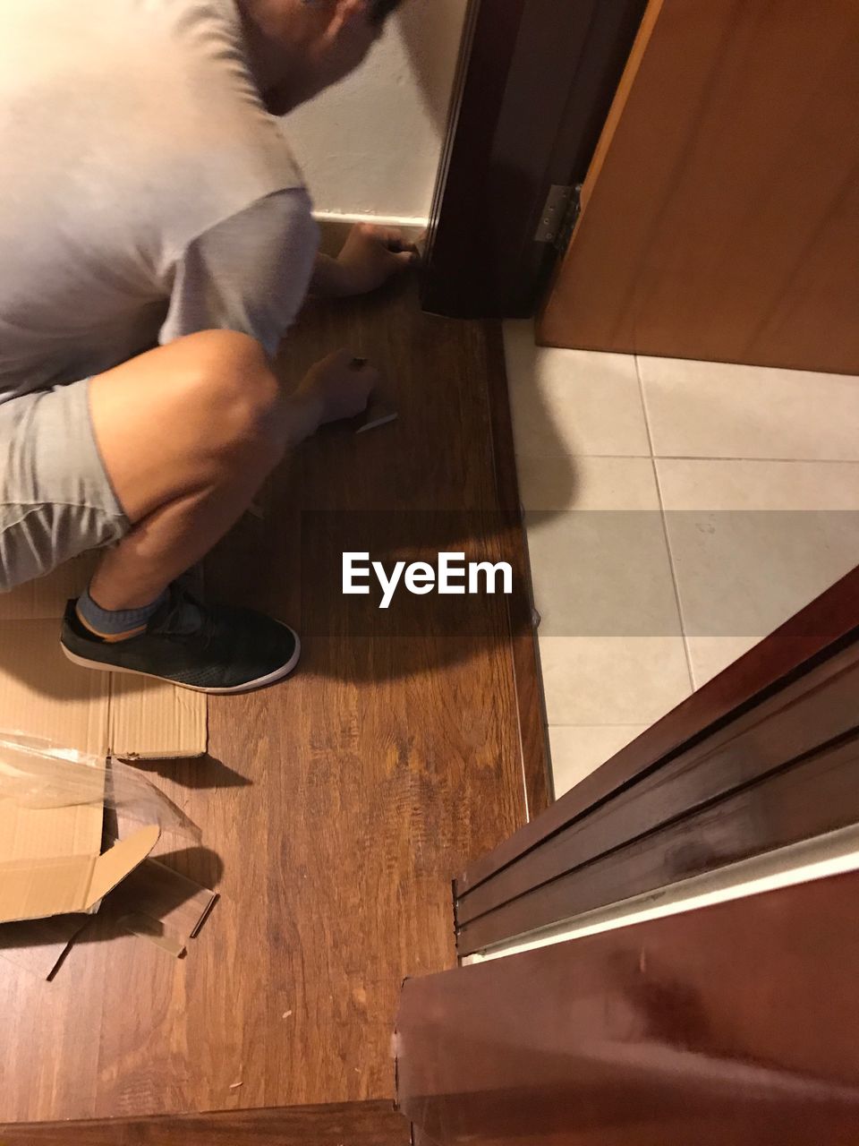 LOW SECTION OF MAN WORKING AT HARDWOOD FLOOR