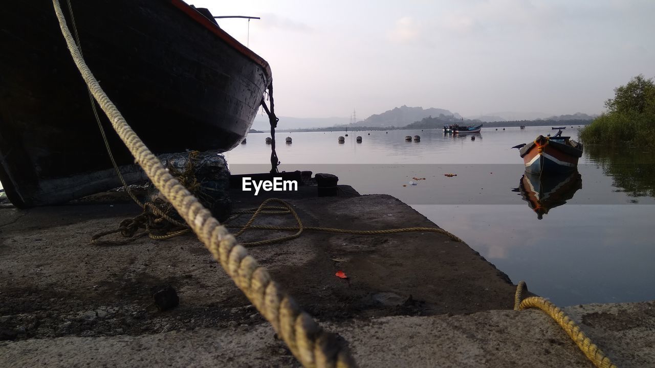 Boat tied with rope at harbor against sky