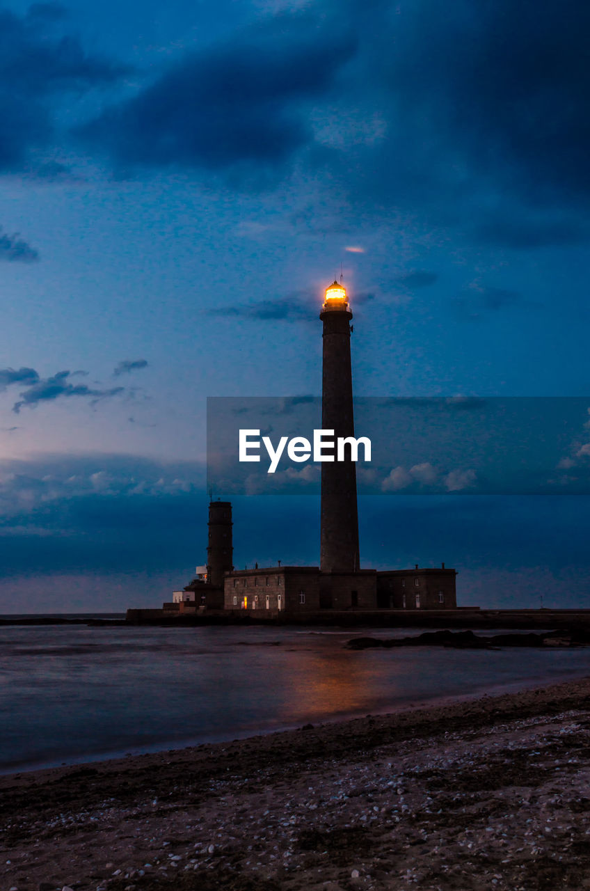 LIGHTHOUSE ON BEACH AGAINST SKY AT NIGHT