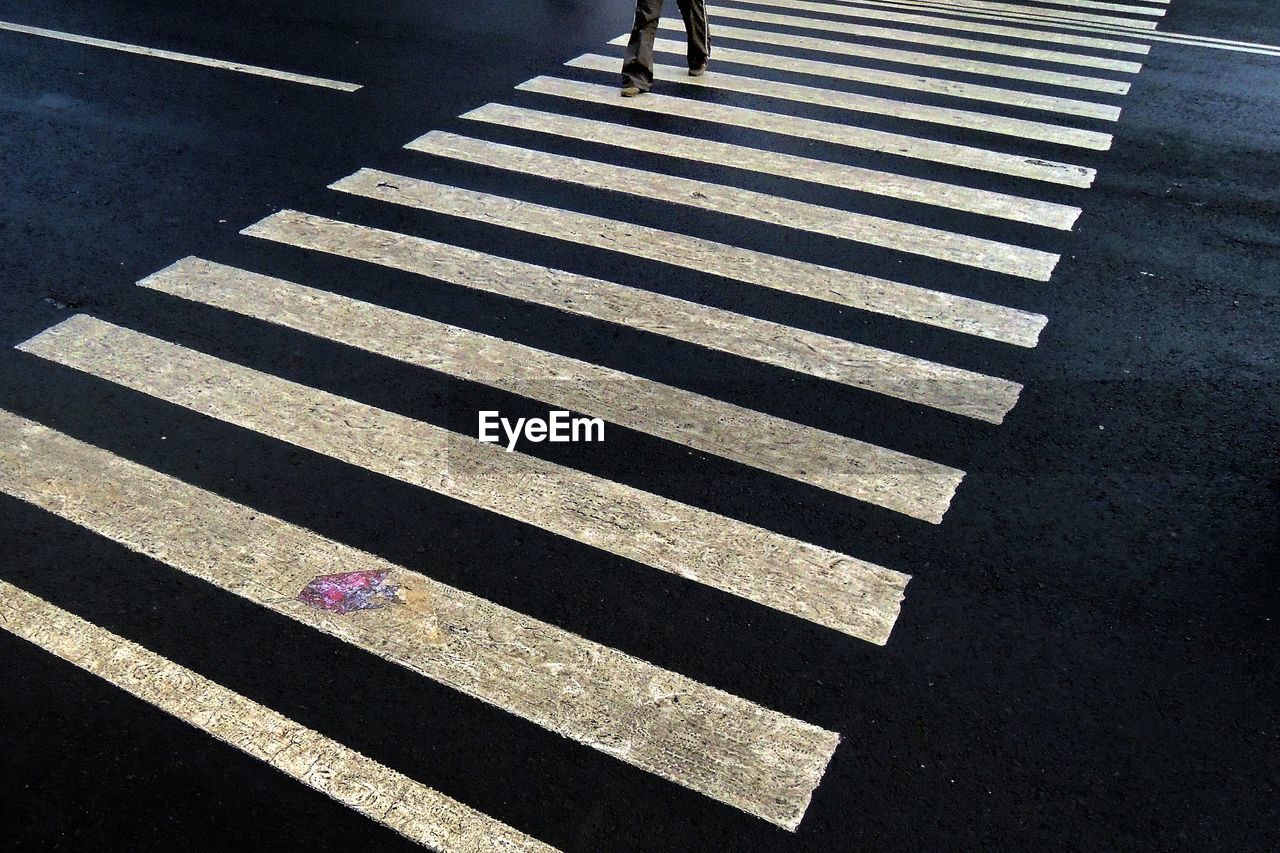 Low section of man walking on zebra crossing