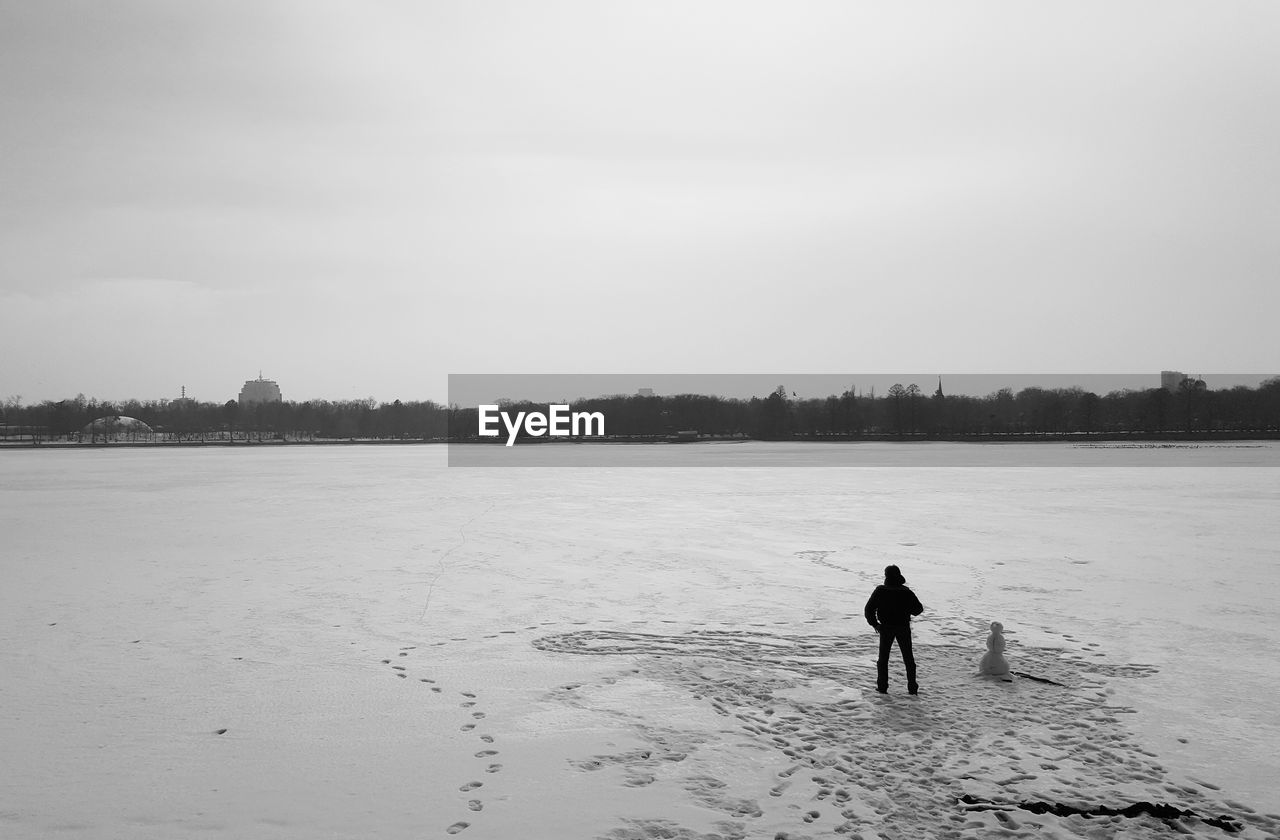 REAR VIEW OF MAN ON LAND AGAINST SKY