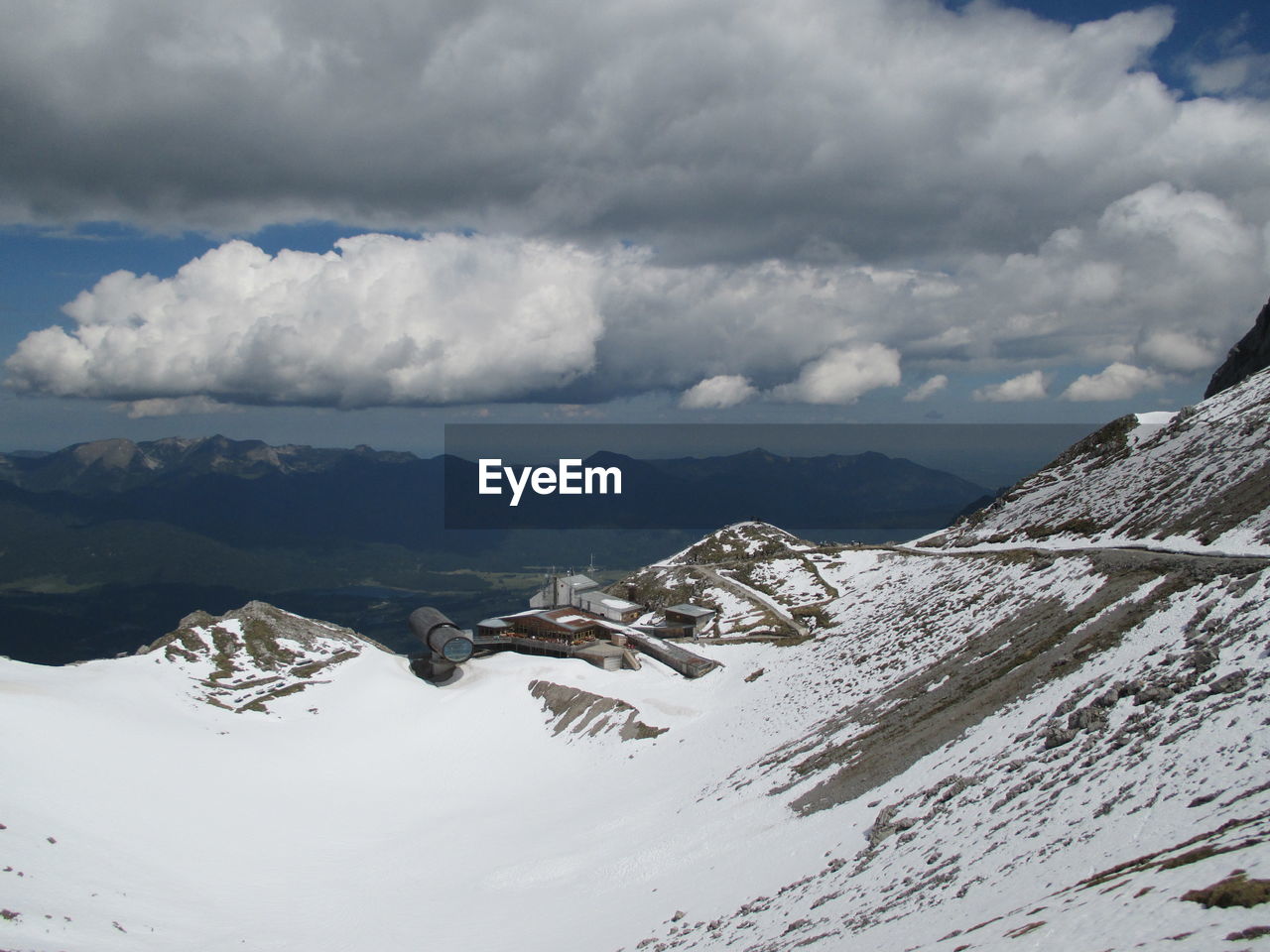 Scenic view of snow covered mountains against cloudy sky