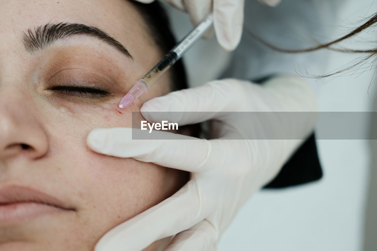 Cosmetologist applying eye mesotherapy to female patient