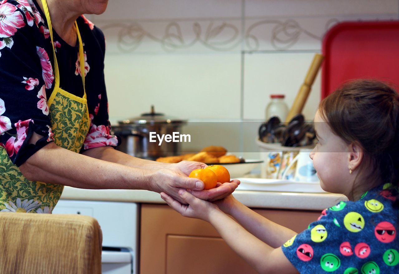 An elderly woman with her granddaughter in the kitchen are engaged in cooking,