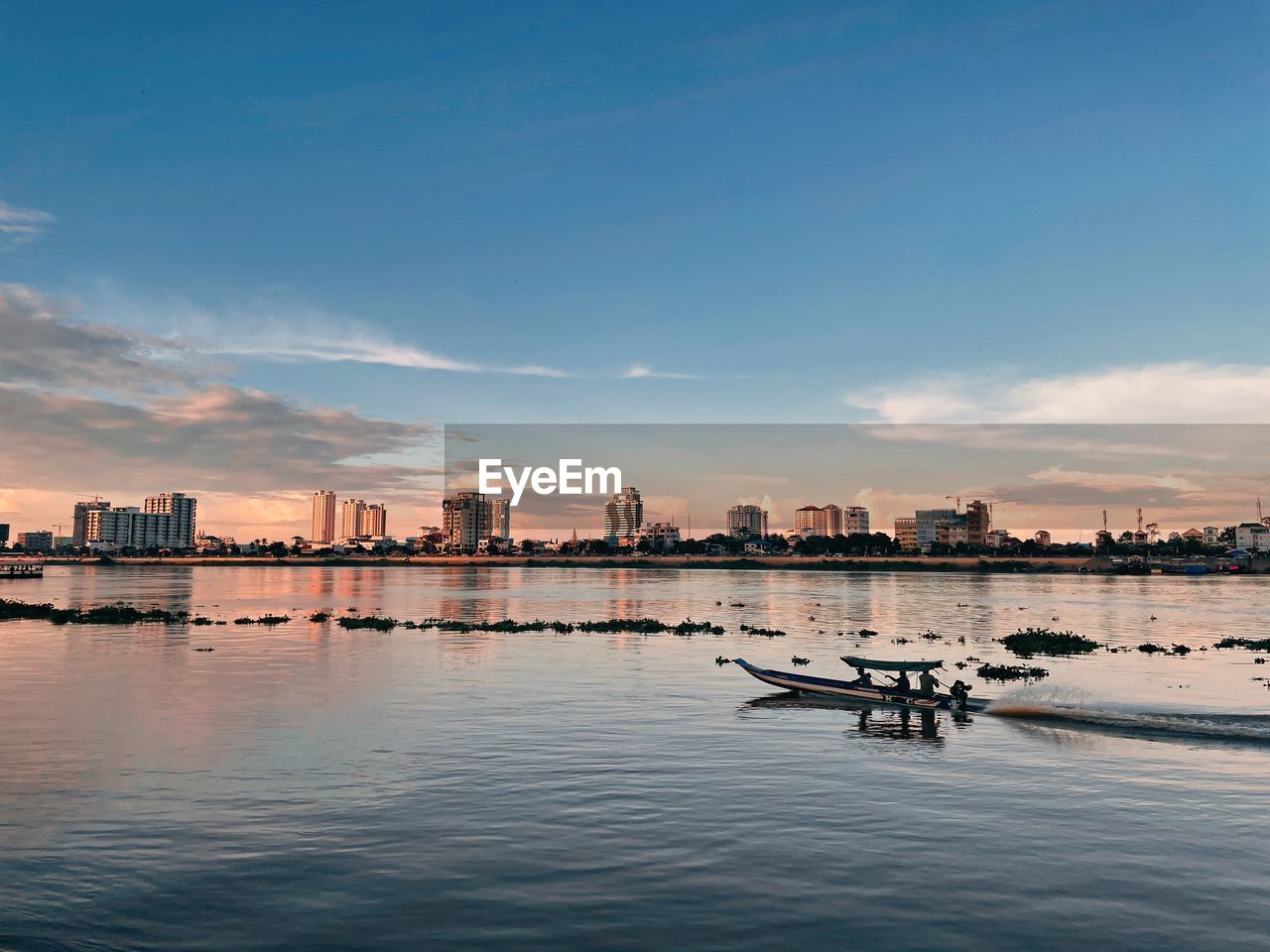 Scenic view of river by buildings against sky