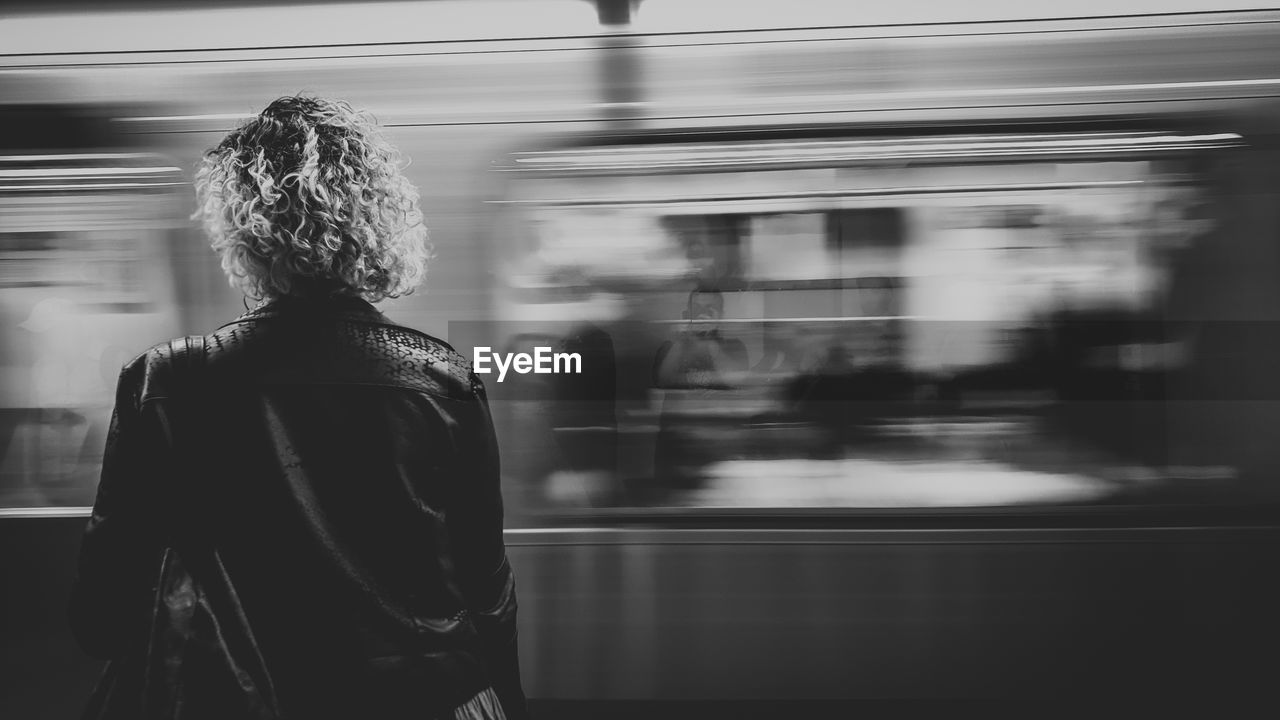 Rear view of woman standing on train at railroad station