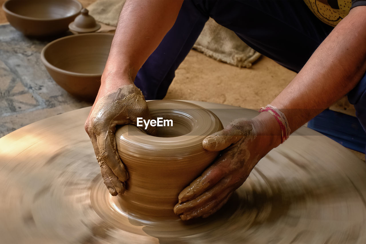 potter's wheel, art, craft, pottery, spinning, occupation, skill, clay, working, molding a shape, making, earthenware, wheel, craftsperson, expertise, creativity, one person, workshop, ceramic, hand, adult, motion, mud, indoors, terracotta, pitcher - jug, craft product, industry, business, blurred motion, men, holding