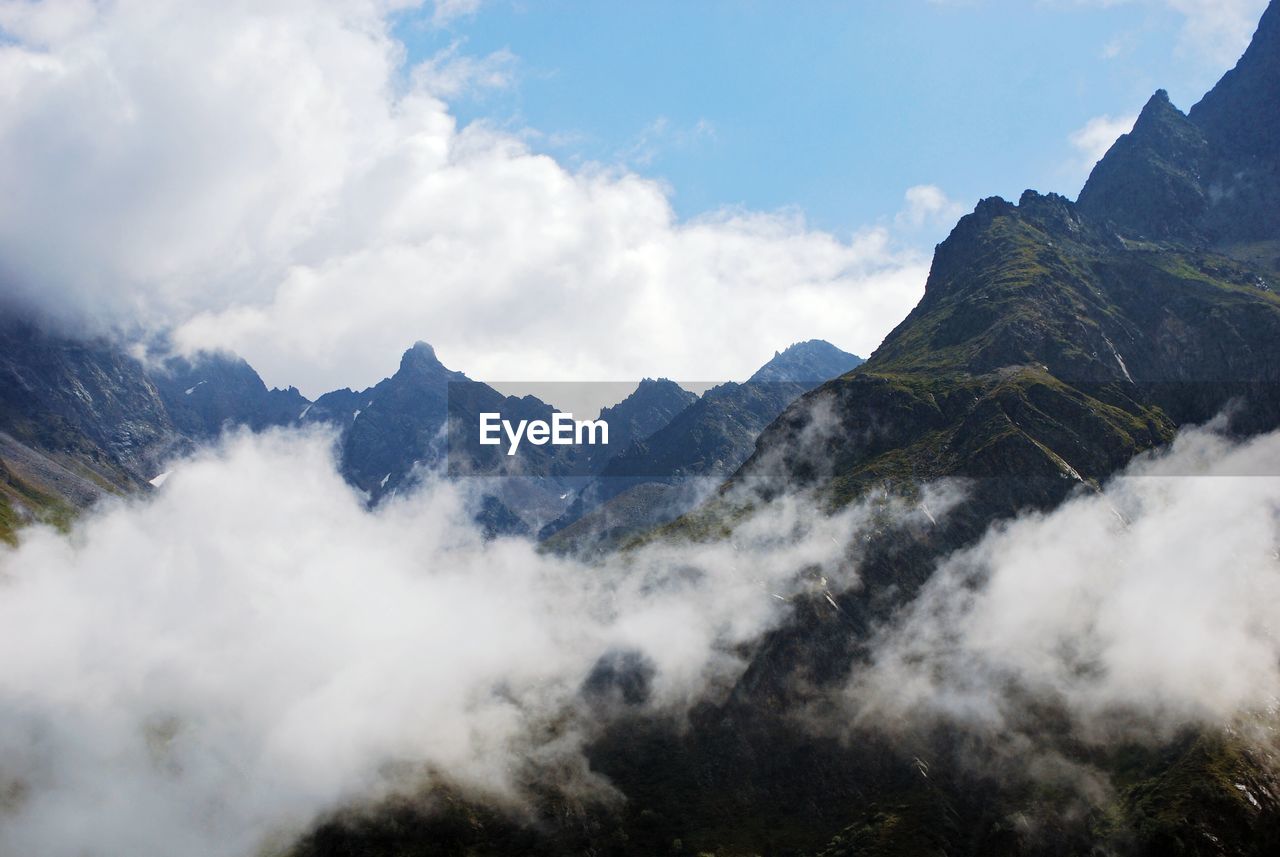 Scenic view of clouds touching mountains