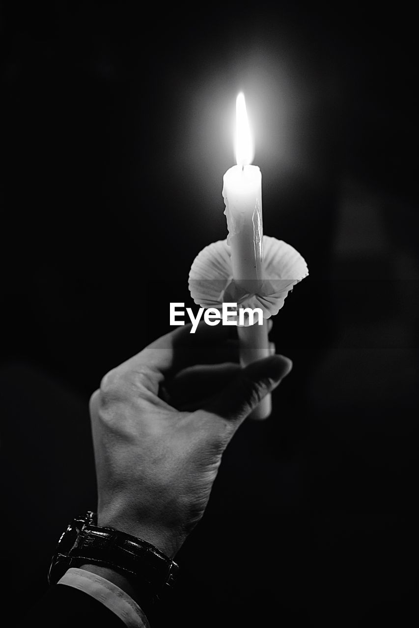 Close-up of hands holding lit candle