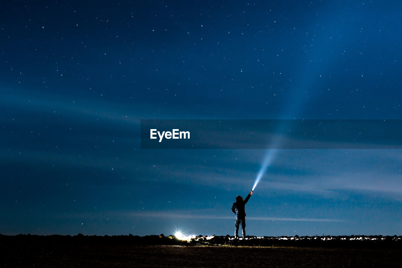 SILHOUETTE MAN STANDING ON FIELD AT NIGHT