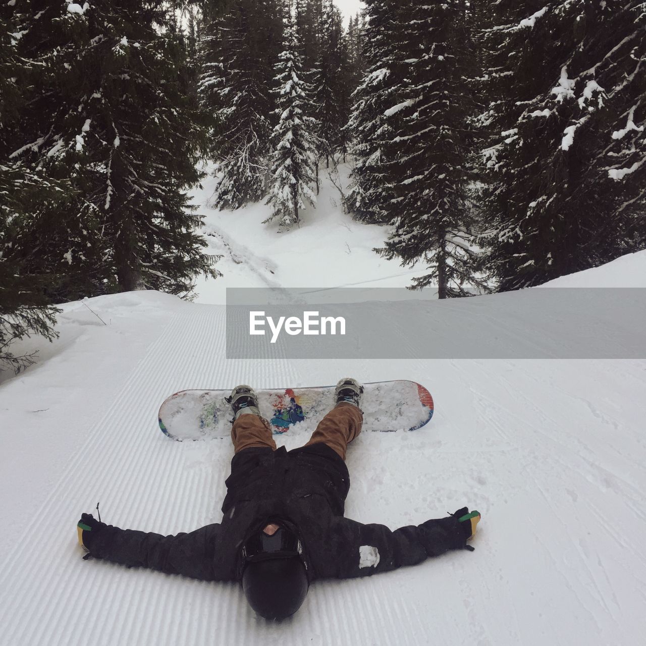 Man lying in snow with snowboard