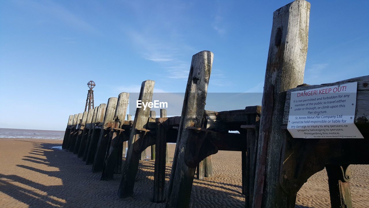 WOODEN POST BY TEXT AGAINST SKY