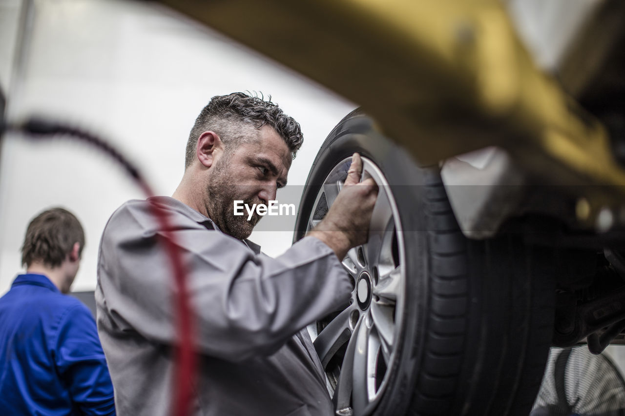 Car mechanic in a workshop changing tire