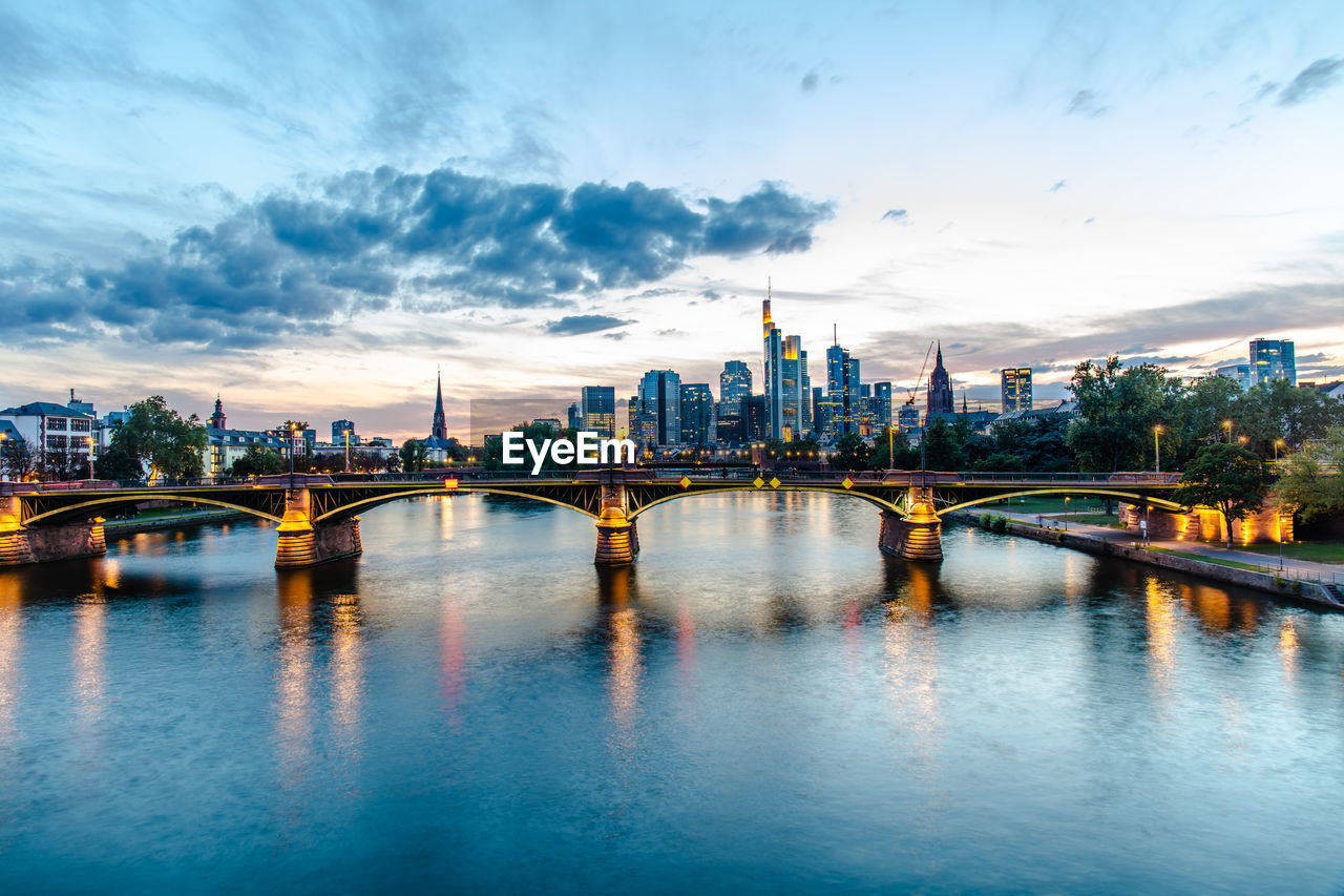 ARCH BRIDGE OVER RIVER BY BUILDINGS AGAINST SKY