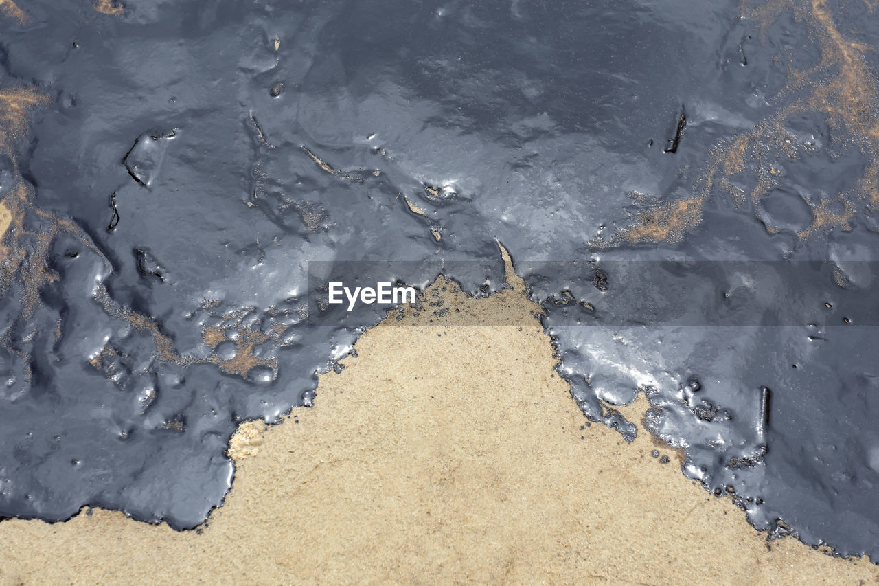HIGH ANGLE VIEW OF SNOW ON WET SAND