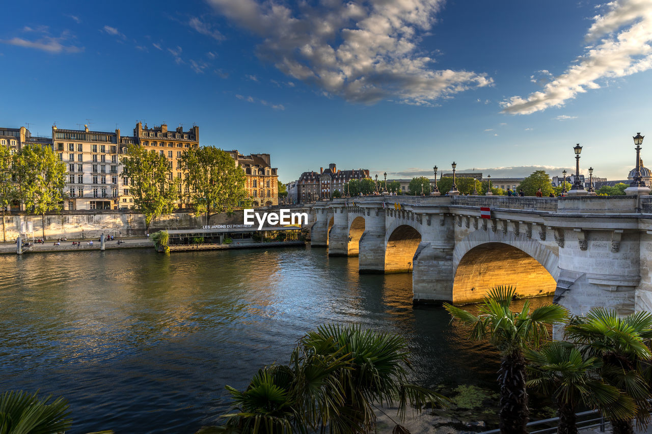 Arch bridge over river against cloudy sky