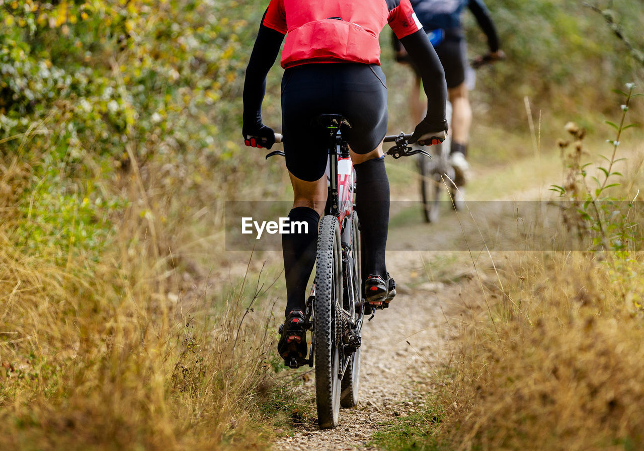 low section of woman riding bicycle on field