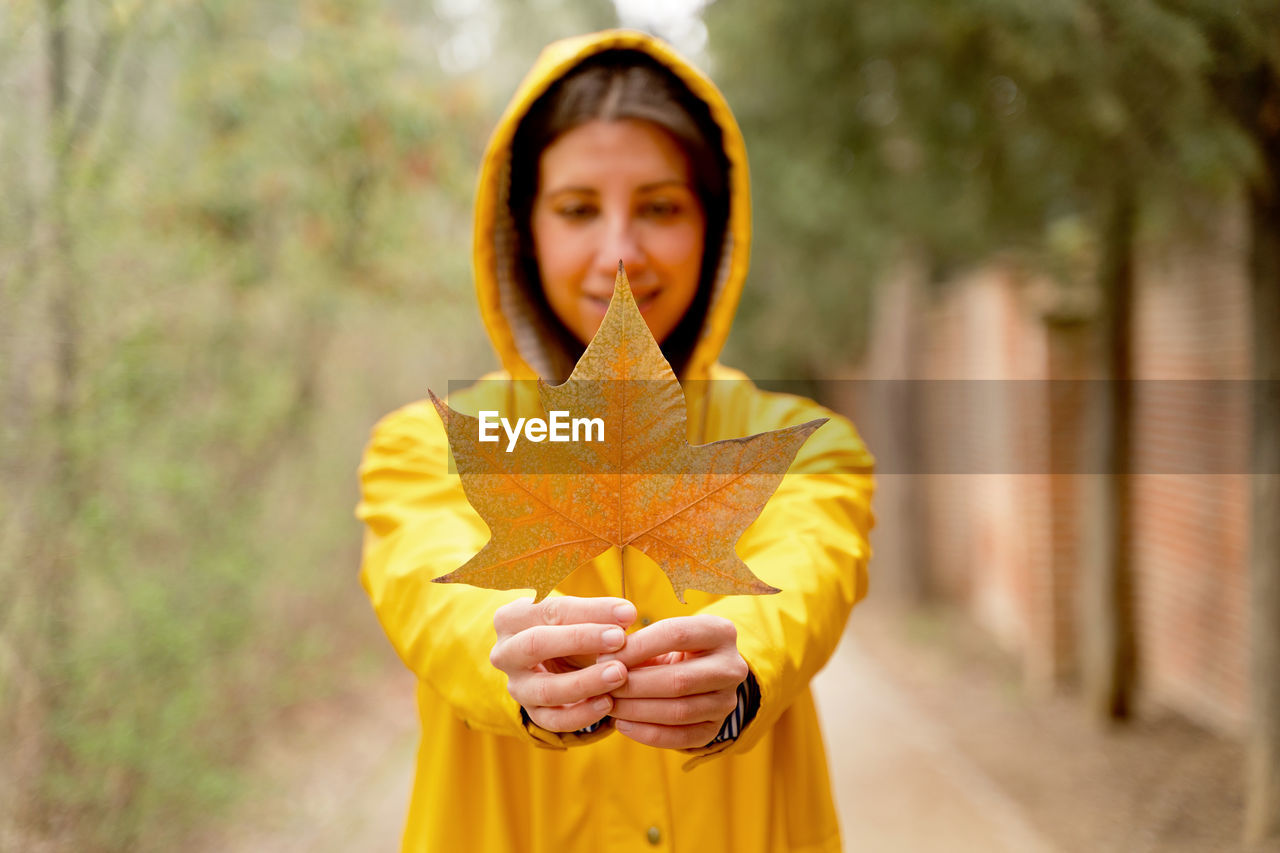 Woman holding autumn leaf in forest