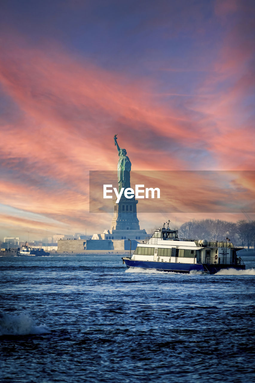 Statue of liberty and boat at hudson river against sky during sunset, new york, usa