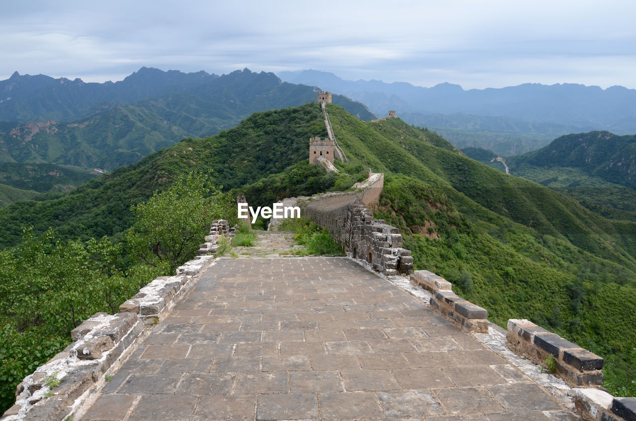 High angle view of great wall of china by mountains against cloudy sky